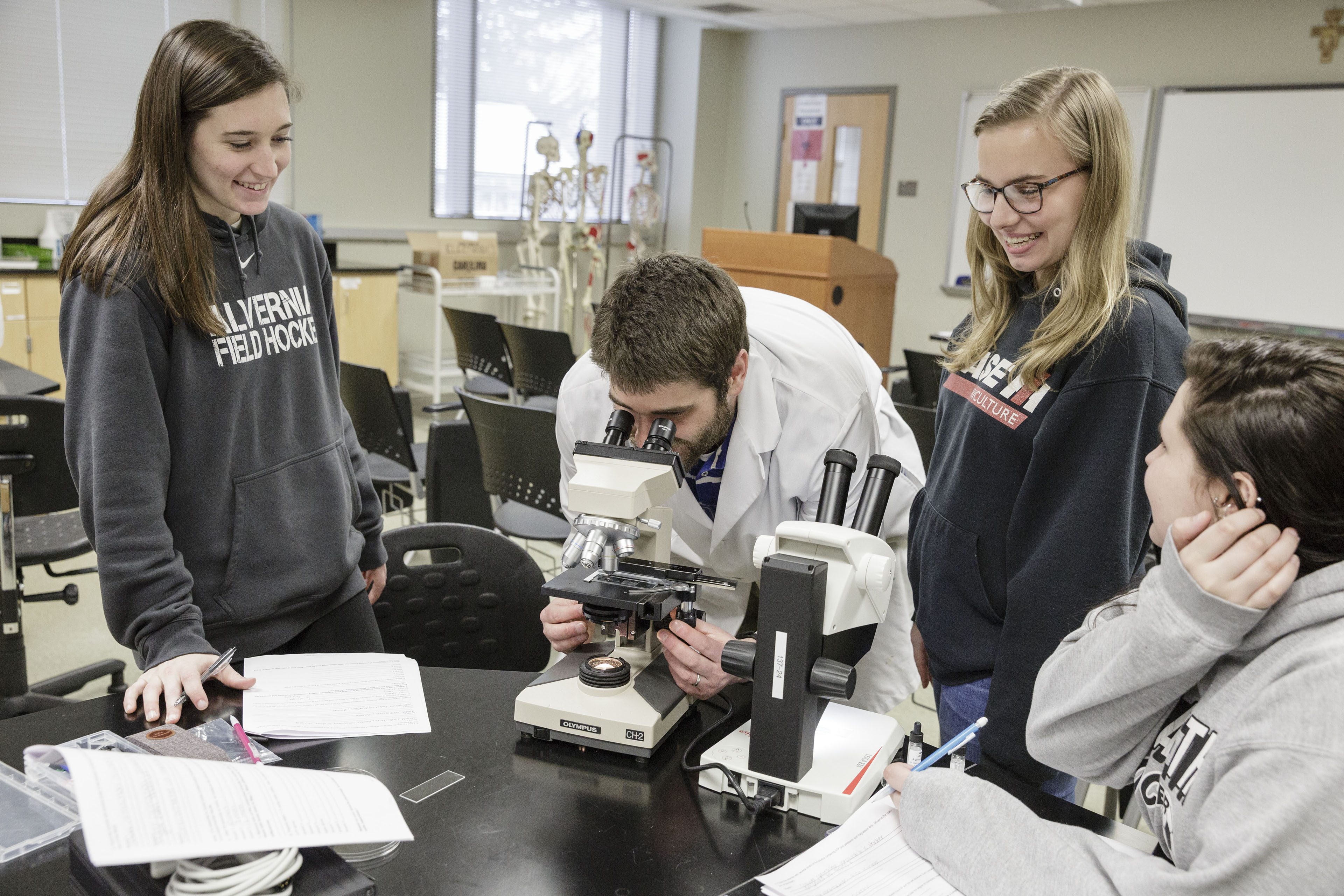 Biology professor demonstrating to students how to use a microscope.