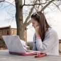 A female student works at her laptop near Francis Hall.