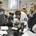 Biology professor demonstrating to students how to use a microscope.