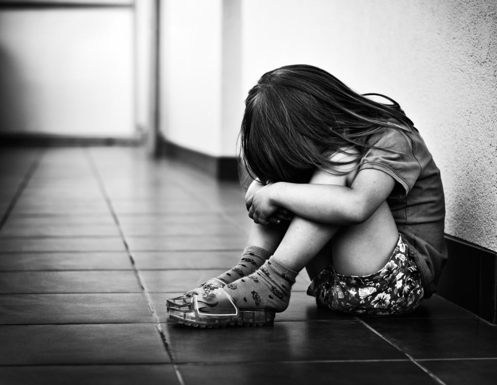 Child sitting on floor with head in hands