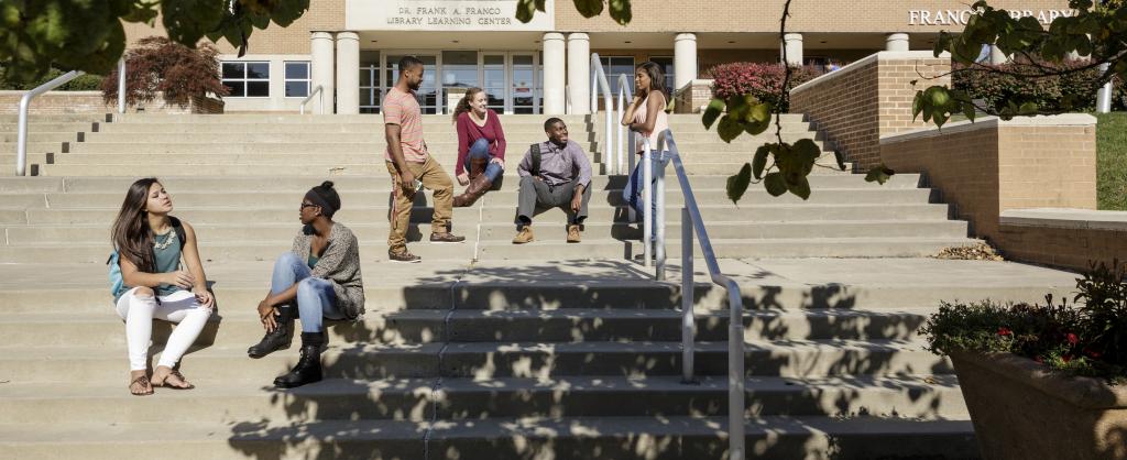A group of diverse students chat on Alvernia's library stairs.