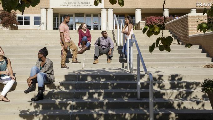 A group of diverse students chat on Alvernia's library stairs.
